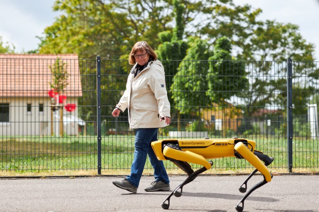 Seniorin geht auf der Straße mit einem Roboterhund spazieren